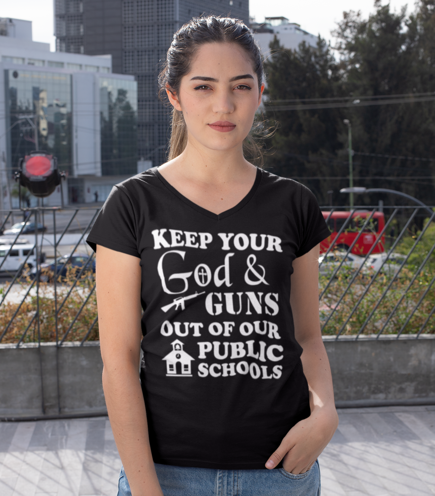 Woman wearing black v-neck shirt with stylized imprint that says  Keep Your God and guns ou too our public schools