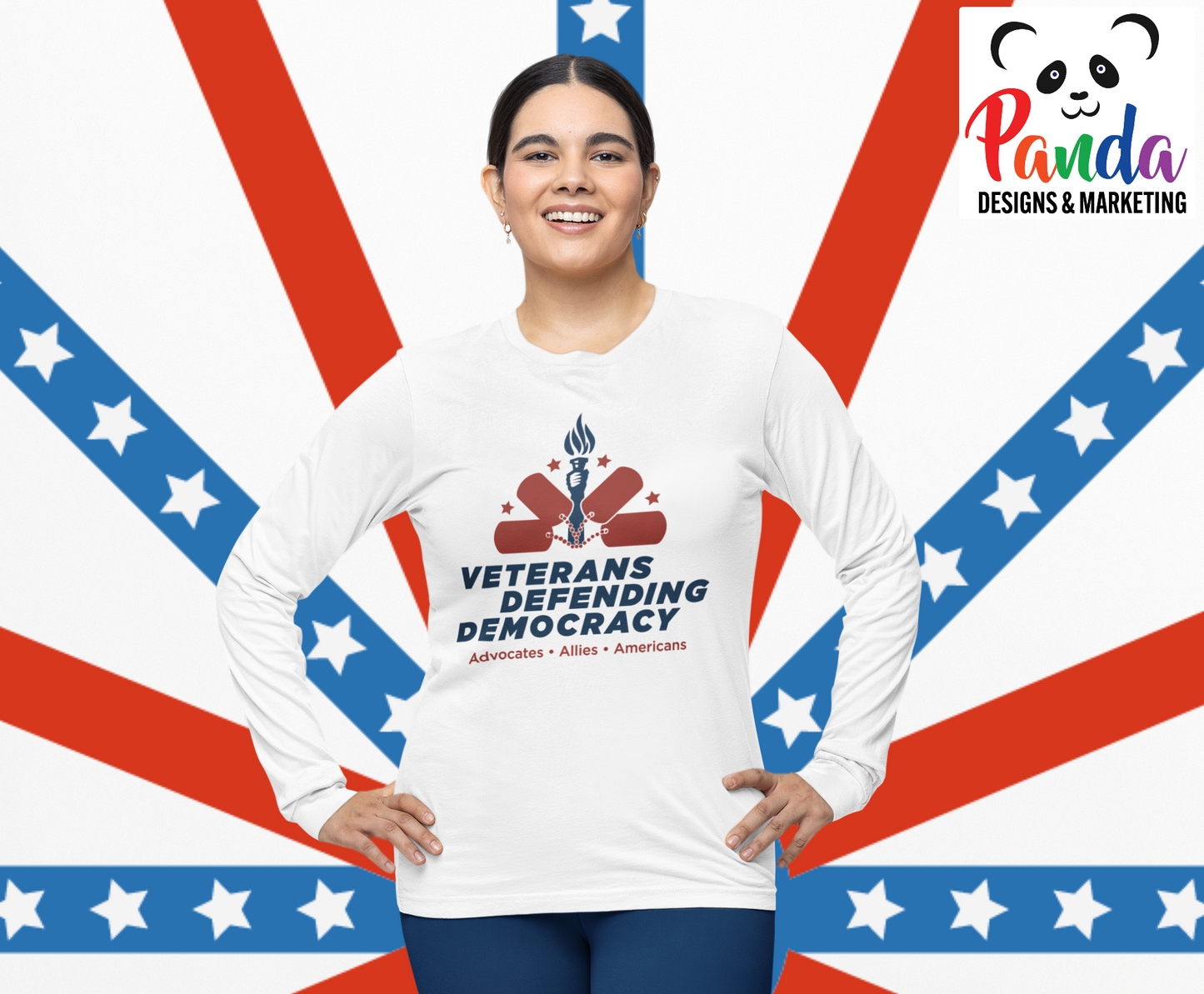 Woman waring white long sleeve sublimated shirt with the Veterans Defending Democracy logo.  The logo is blue and red and features a hand holding a torch with a half circle arch of dog tags and stars.  The text Advocates . Allies. Americans is under the logo. 