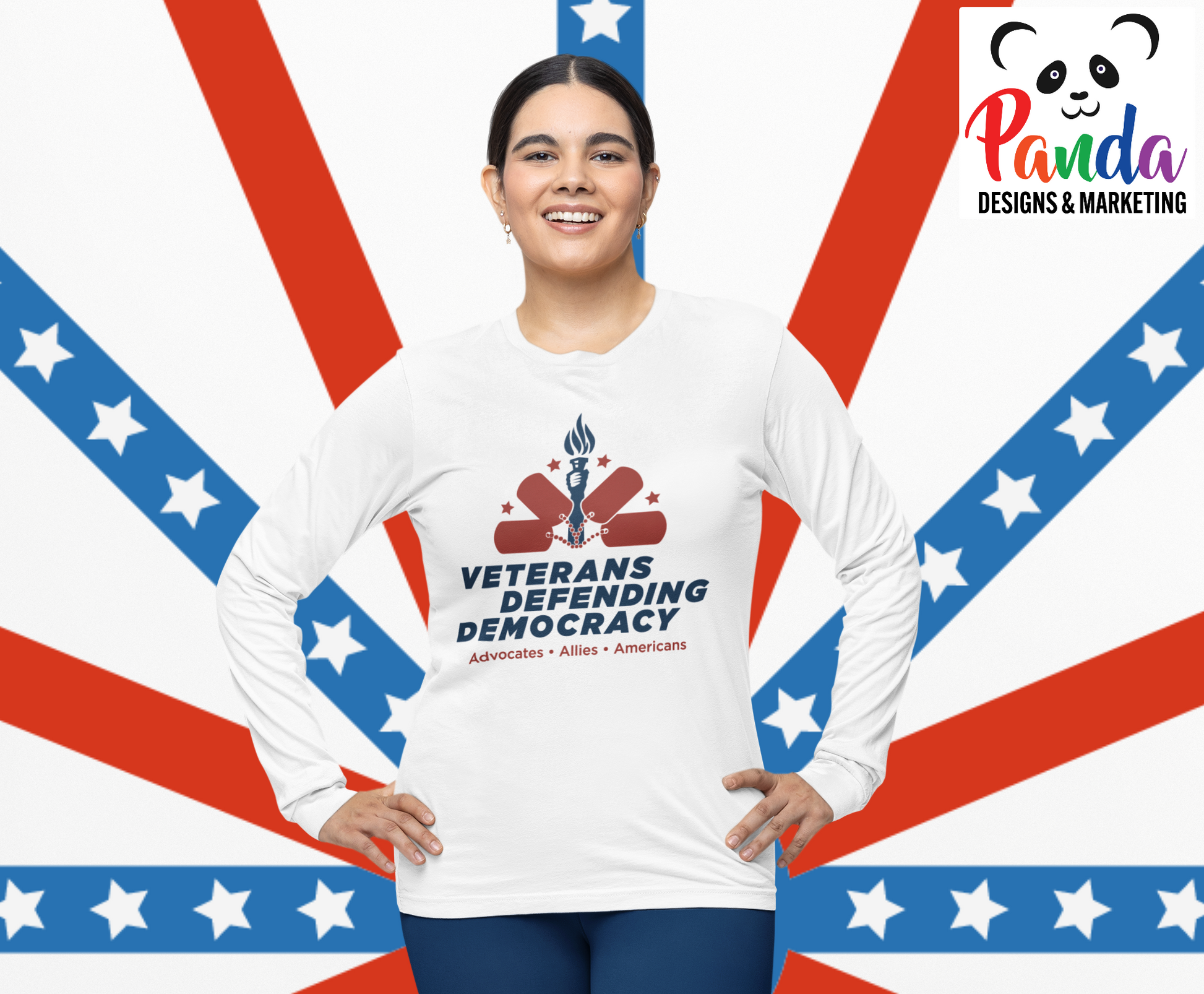 Woman waring white long sleeve sublimated shirt with the Veterans Defending Democracy logo.  The logo is blue and red and features a hand holding a torch with a half circle arch of dog tags and stars.  The text Advocates . Allies. Americans is under the logo. 