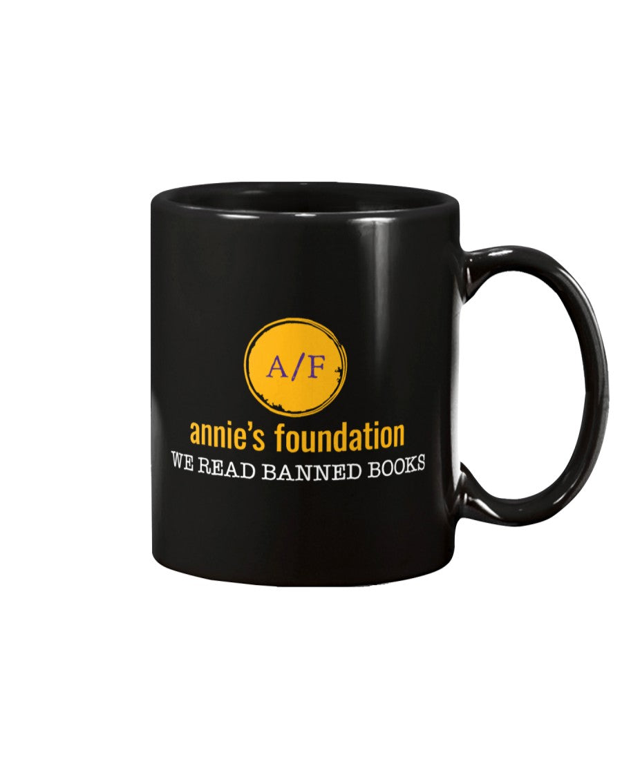 15 oz black mug featuring the yellow version of the Annie's Foundation logo and we read banned books